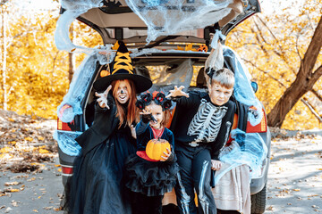 siblings boy in skeleton costume, teenage girl in witch costume and hat and cute little girl in...