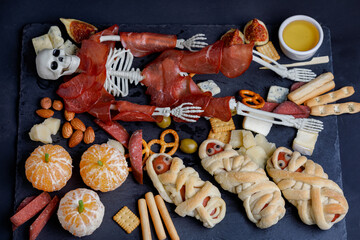 Snack Halloween Plate With Skeleton And Egyption Mummy From Food On Black Background. Flat Lay.