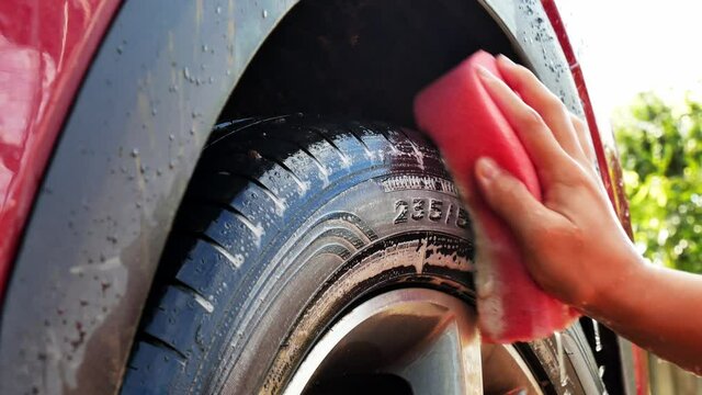 Worker washing car's wheels with sponge on a car wash. Car Wash Business Banner.