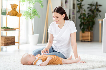 Photo of dreamy cute lady wear white t-shirt smiling sitting floor playing baby inside indoors...