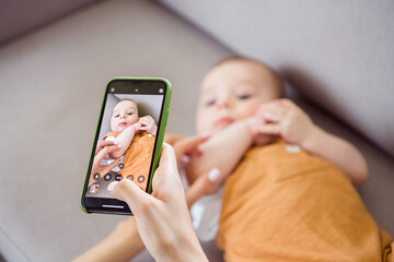 Photo of pretty sweet mother dressed white t-shirt recording video child lying couch smiling inside indoors apartment room