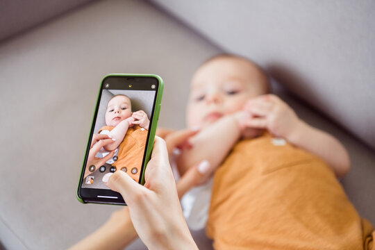 Photo of pretty sweet mother dressed white t-shirt recording video child lying couch smiling inside indoors apartment room
