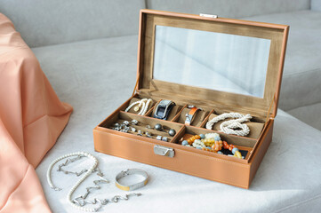 Leather jewelry box with jewelry and accessories laid on a couch