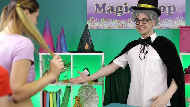 Two girls and a young man stand in a magic shop. Halloween.