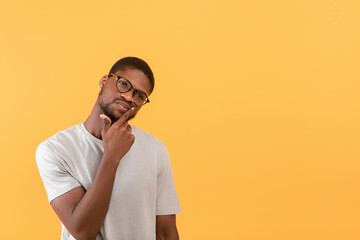Pensive african american man looking aside at free space and touching chin, thinking about offer...