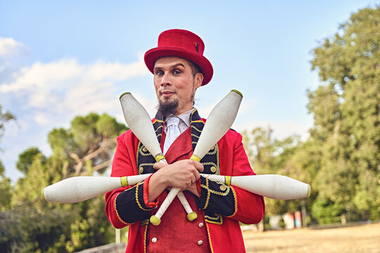 Male juggler with clubs in park