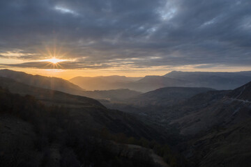 Fototapeta na wymiar Last rays of the setting sun over a mountainous plateau. Golden sunset in mountain landscape. Silhouette of the evening mountains at sunset. Matlas Valley at sunset in Dagestan.