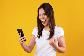 Happy excited lady using mobile phone at studio, saying yes