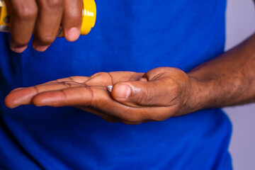 african american man in blue shirt pouring pills from prescription pill bottle