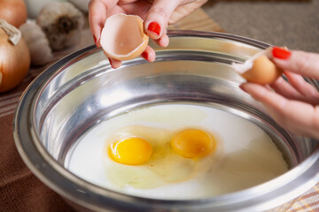 Two broken chicken eggs in  metal bowl..