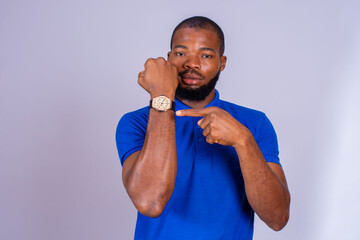 young black man eagerly pointing to his watch, suggesting that you hurry concept