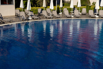 Empty sun loungers near the pool with blue water