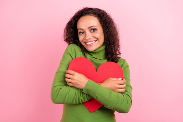 Photo of dreamy sweet african lady dressed green turtleneck smiling embracing large paper heart isolated pink color background