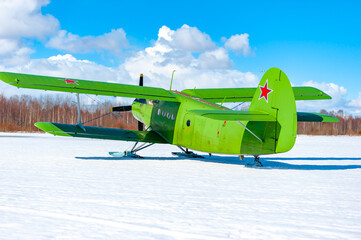 An old classic airplane. A military biplane stands in the snow on skis in winter against the sky -...
