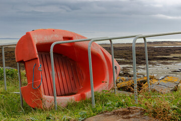 Fototapeta na wymiar Petite annexe de bateau de couleur rouge couché sur le flanc face à la mer à Damgan en Bretagne 