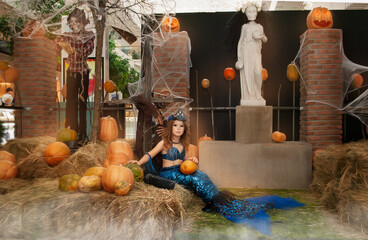 a little girl in a mermaid costume for the holiday of evil spirits Halloween. Sweets or life in the costume of a terrible mermaid
