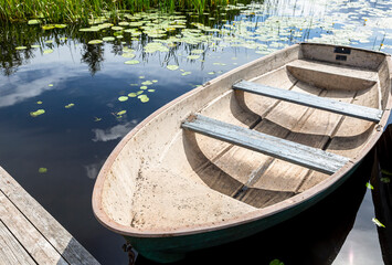 Old plastic fishing boat on the bank of the lake