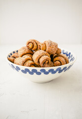 Fresh sweet baked pastry.  Small croissants in plate on light background. Russian traditional dessert rogaliki. 
