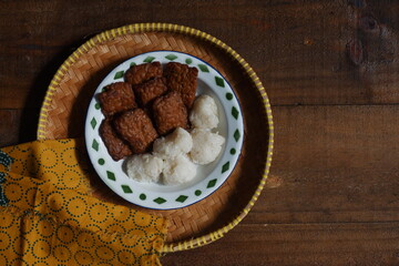 a plate of tempeh cooked in brown spice served with glutinous rice balls