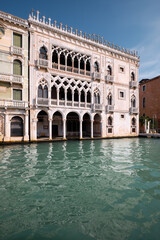 Fototapeta na wymiar Architecture of Venice, Italy. Palazzo, historic house reflected in the water of Grand Canal. Traditional Venetian architecture. Bright sunny day with blue sky.