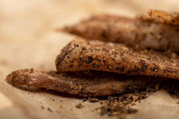 thinly sliced homemade lard with pepper on white oiled paper, close-up, selective focus.