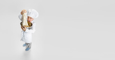 Flyer with little boy in white cook, chef jacket and hat standing isolated on white studio background.