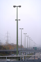 Column of street lights at city highway at Zürich Wallisellen on a foggy grey autumn day. Photo taken October 29th, 2021, Zurich, Switzerland.