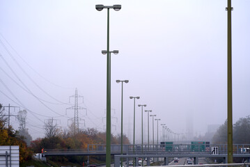 Column of street lights at city highway at Zürich Wallisellen on a foggy grey autumn day. Photo taken October 29th, 2021, Zurich, Switzerland.