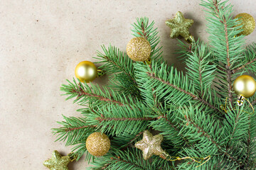 corner of fir tree branch with gold decoration on craft paper for christmas card with copy space for text.