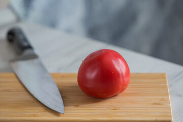 red tomato  and knife on a cutting board