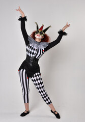 Obraz premium halloween, character, costume, figure pose, posing, portrait, gesture, isolated, magical, dynamic movement, isolated, studio background, red hair, circus, theatre, jester, clown, full length,