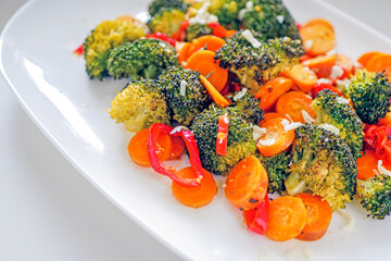 Baked vegetables broccoli, peppers, tomatoes, carrots close-up. Healthy food, vegan cuisine background.