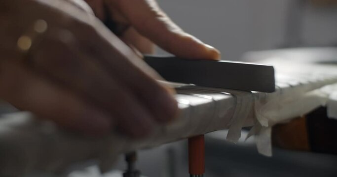 Luthier grinds guitar frets at musical instruments repair shop, 4k 60fps 10 bit