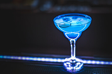 Blue lagoon cocktail with blue curacao liqueur, vodka, lime juice and soda on bar counter