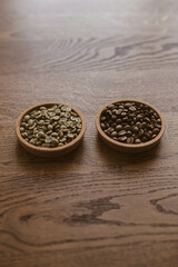 Green coffee beans next to roasted coffee beans on a stand on a wooden table. Unroasted coffee. Roasted coffee. Raw coffee.