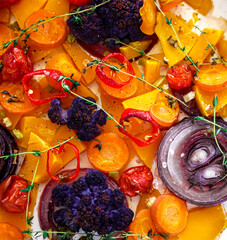 Baked orange and purple vegetables close-up. Cauliflower, red onion, pumpkin, grilled tomatoes, homemade healthy food, vegan food background