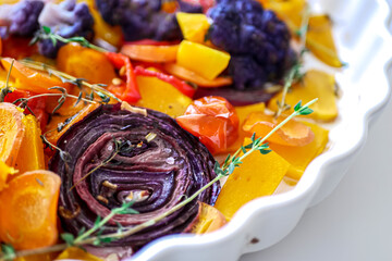 Baked orange and purple vegetables close-up. Cauliflower, red onion, pumpkin, grilled tomatoes, homemade healthy food, vegan food background