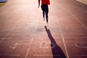 A young athlete is running during a training on the race track at the stadium. Sport, athletics,...