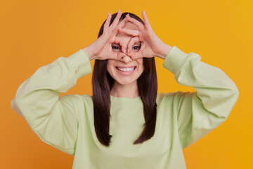 Photo of young lovely girl have fun show fingers binoculars sign cool grimace isolated over yellow color background