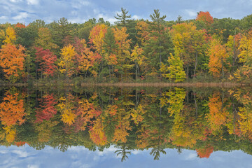 Autumn landscape of the shoreline of Long Lake with mirrored reflections in calm water, Yankee Springs State Park, Michigan, USA