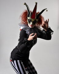 close up portrait of red haired  girl wearing a black and white clown jester costume, theatrical...