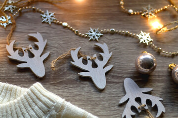 White cable knit sweater and various Christmas decorations on wooden background. Selective focus.