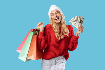 Cheerful woman holding money carrying shopping bags in winter