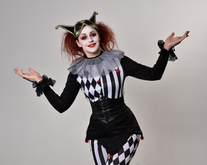 close up portrait of red haired  girl wearing a black and white clown jester costume, theatrical...