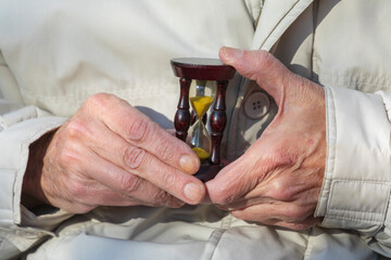 Hourglass in the hands of an old man who understands that life is short