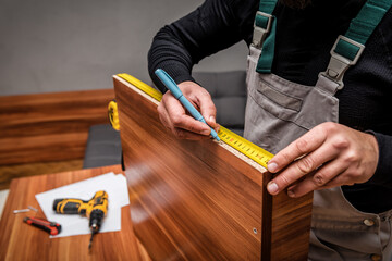 Fototapeta na wymiar the furniture maker measures details with a tape measure