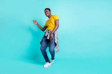 Full length photo of nice brunette hairdo millennial man dance wear yellow t-shirt jeans sneakers isolated on cyan color background