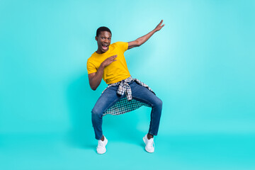 Full body photo of cool brunette hairdo millennial man dance wear yellow t-shirt jeans sneakers isolated on cyan color background