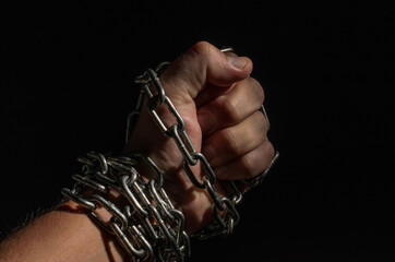 Human hand chained in metal chains isolated on black background