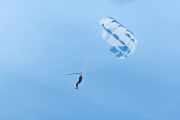 Parachute over the sea against a blue sky . Flying with parachute tied to a boat in summer vacation